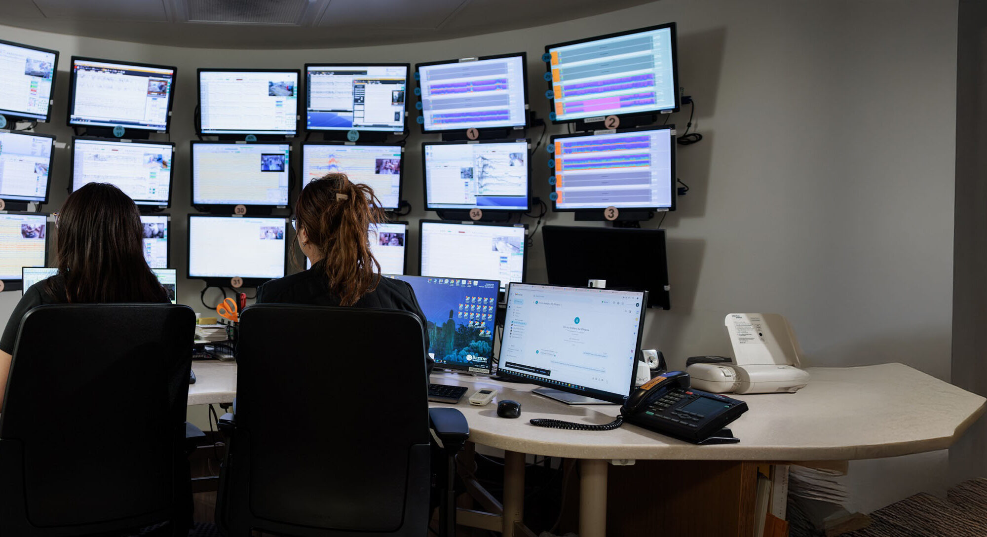 photograph of two nurses observing patient data in the monitoring room on the epilepsy monitoring unit