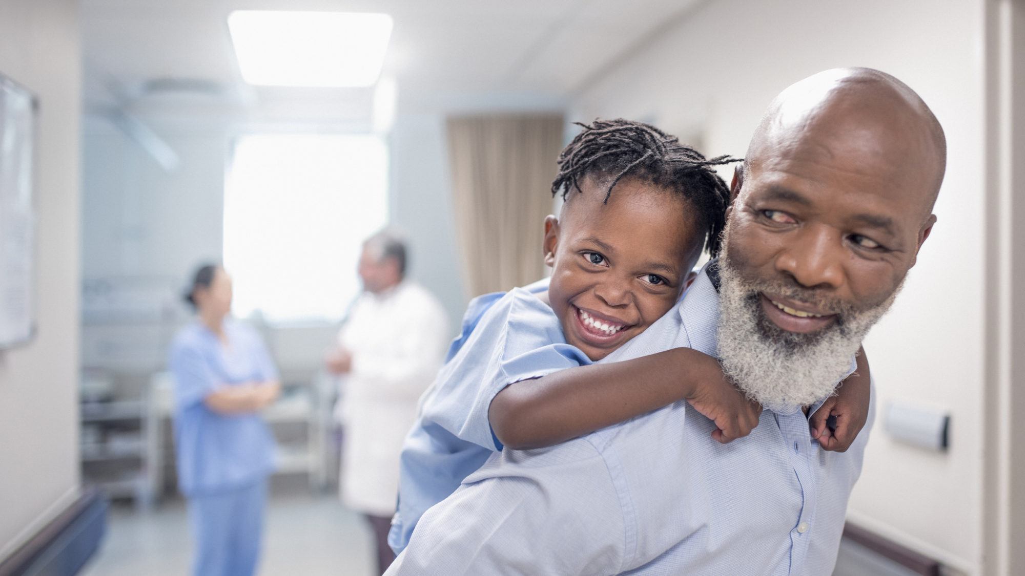 father giving his son a piggyback ride in the hospital