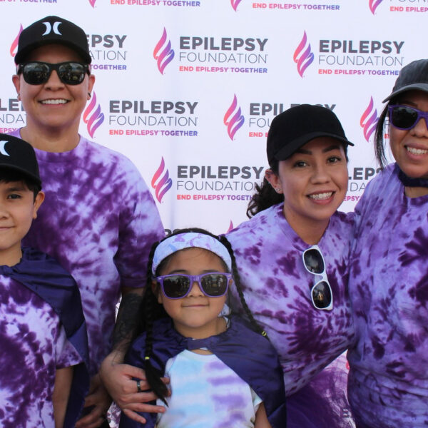 Marissa Amaya Ochoa and her family don tie-dye shirts and stand in front of an Epilepsy Foundation banner at a Walk to End Epilepsy event in Phoenix.