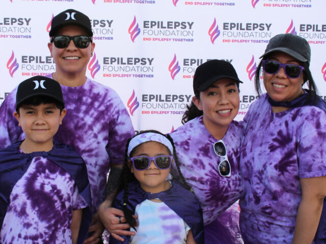 Marissa Amaya Ochoa and her family don tie-dye shirts and stand in front of an Epilepsy Foundation banner at a Walk to End Epilepsy event in Phoenix.